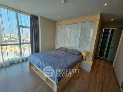Spacious bedroom with large windows and modern decor in urban apartment