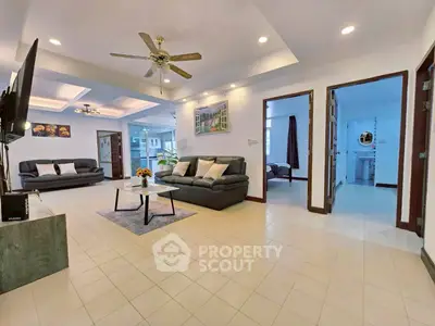 Spacious living room with modern decor and ceiling fans, perfect for family gatherings.