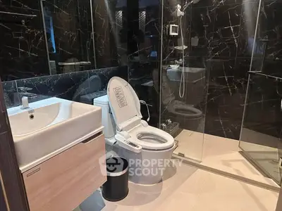 Luxurious modern bathroom with sleek black marble tiles and elegant fixtures.