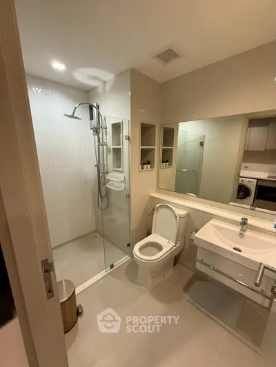 Modern bathroom with glass shower and sleek fixtures in contemporary apartment.