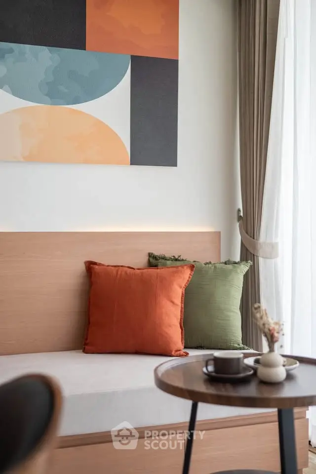 Modern living room with stylish decor and cozy seating area, featuring colorful cushions and abstract wall art.