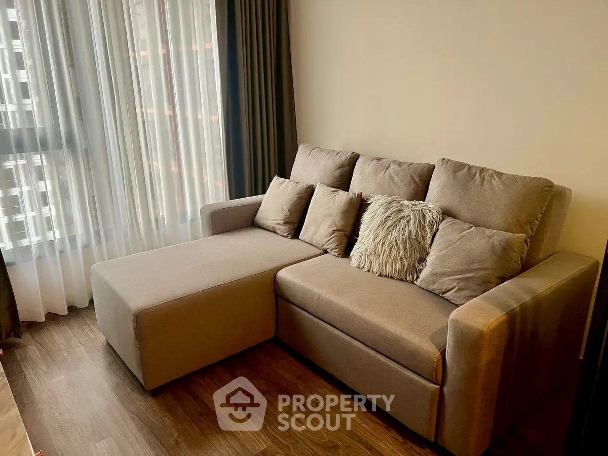 Cozy living room with stylish sofa and natural light from large window.