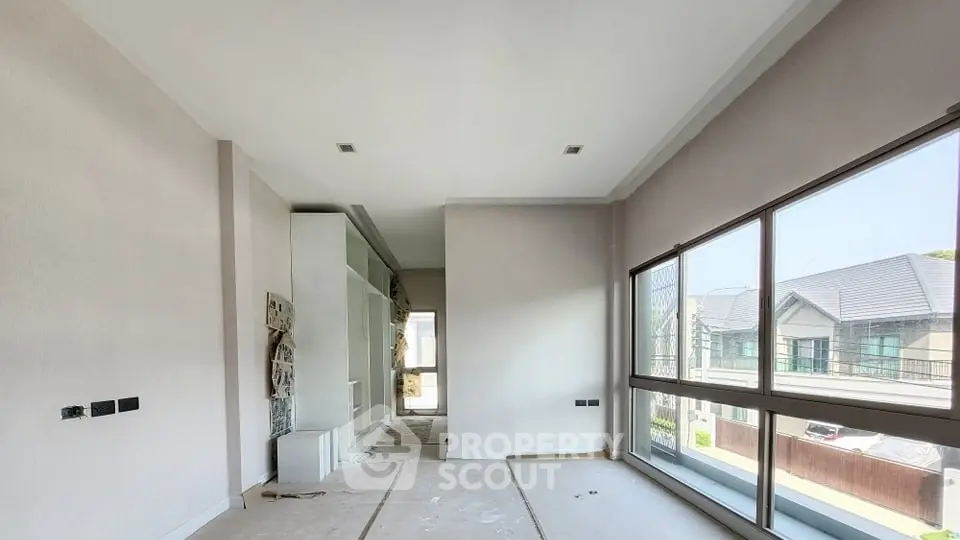 Spacious room with large windows offering a view of modern houses, ideal for customization.