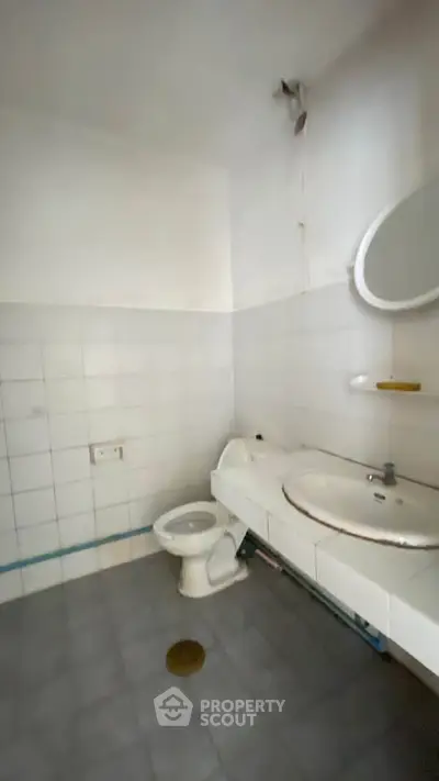 Spacious bathroom with white tiles and modern fixtures, ideal for renovation.