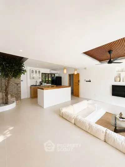 Spacious modern living room with open kitchen, elegant design, and natural light.