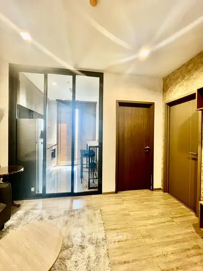 Modern apartment interior with stylish kitchen and cozy living area, featuring sleek wooden flooring and elegant lighting.