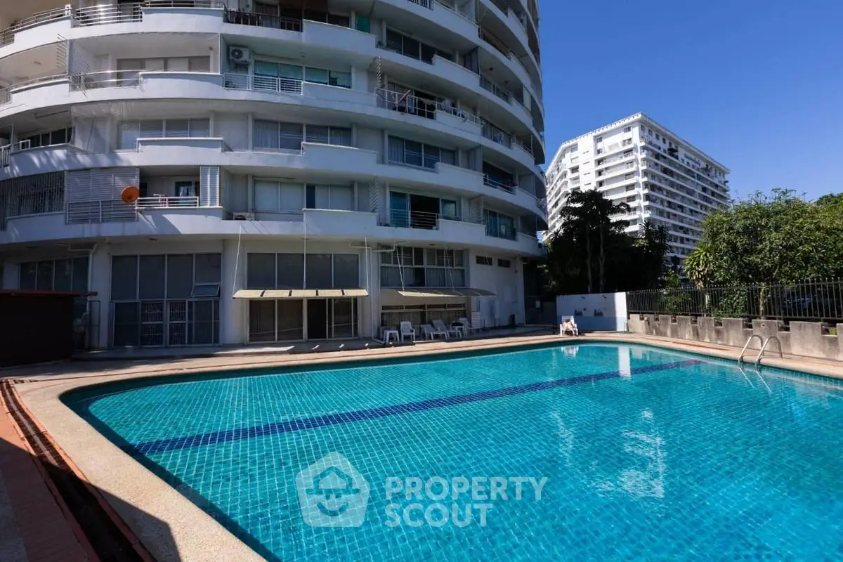Luxurious apartment building with a sparkling outdoor pool and modern architecture.