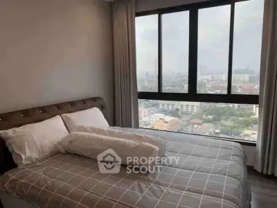 Modern bedroom with large window offering stunning city views, featuring a cozy bed and elegant decor.