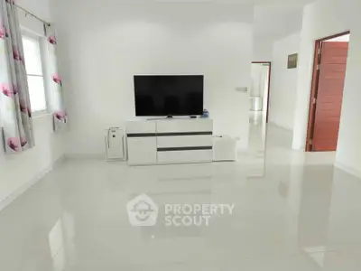 Spacious modern living room with sleek TV setup and glossy tiled floors.