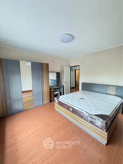Spacious bedroom with modern furniture and wooden flooring, perfect for comfort and style.