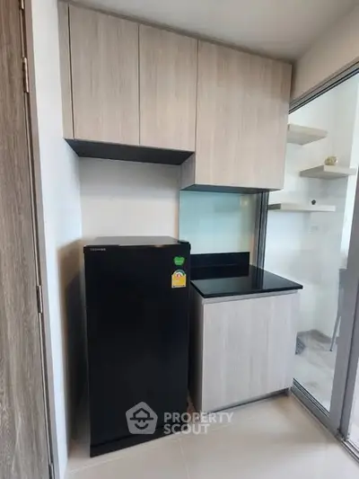 Modern kitchen with sleek cabinetry and compact fridge