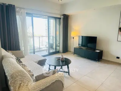 Modern living room with balcony view, featuring cozy seating and sleek TV setup.