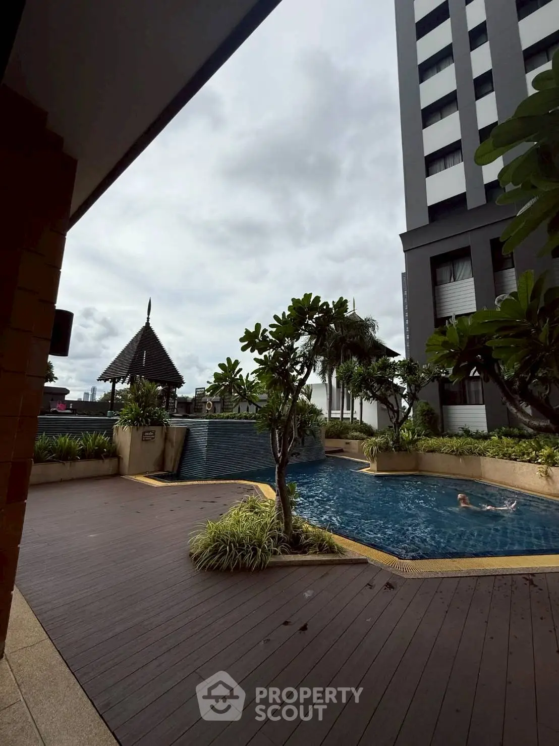 Luxurious residential pool area with lush greenery and modern building exterior.