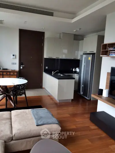 Modern living room with open kitchen, sleek cabinetry, and cozy seating area in a stylish apartment.