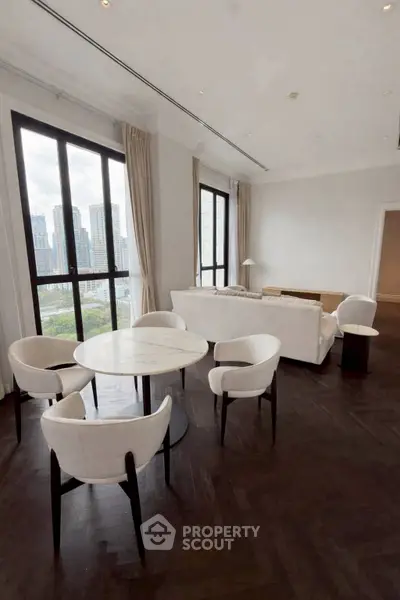 Luxurious living room with city view, elegant furniture, and large windows in high-rise apartment.