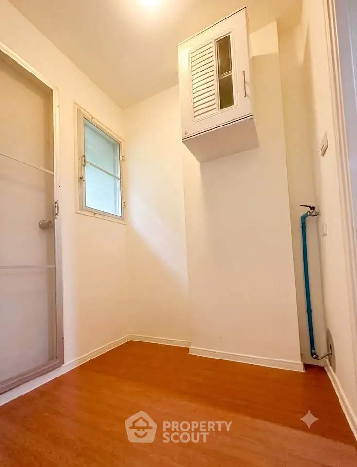 Compact utility room with wooden flooring and storage cabinet, ideal for small appliances or laundry setup.