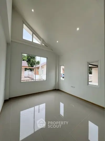 Spacious room with high ceilings and large windows offering natural light and outdoor views.