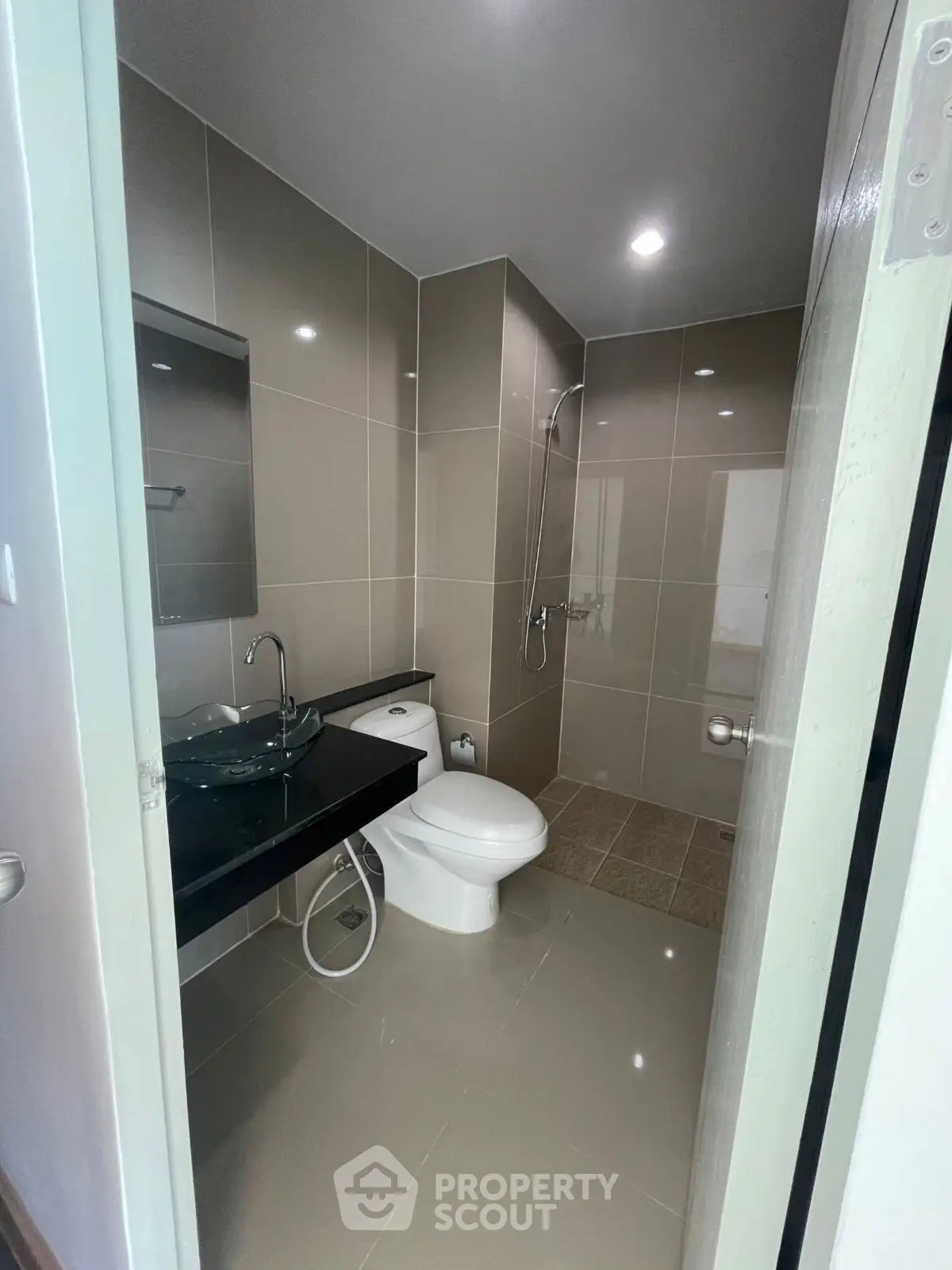 Modern bathroom with sleek design, featuring a glass sink and walk-in shower in a contemporary apartment.