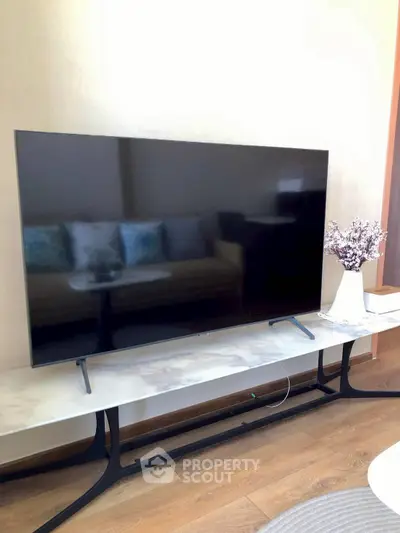 Modern living room with sleek TV and elegant decor on wooden flooring.