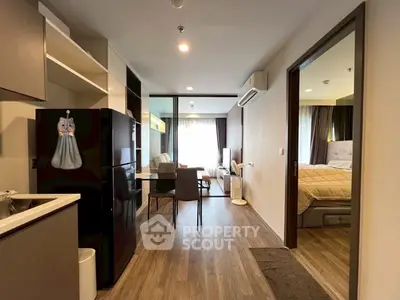 Modern open-plan apartment with stylish kitchen and cozy living area, featuring elegant wooden flooring and natural light.