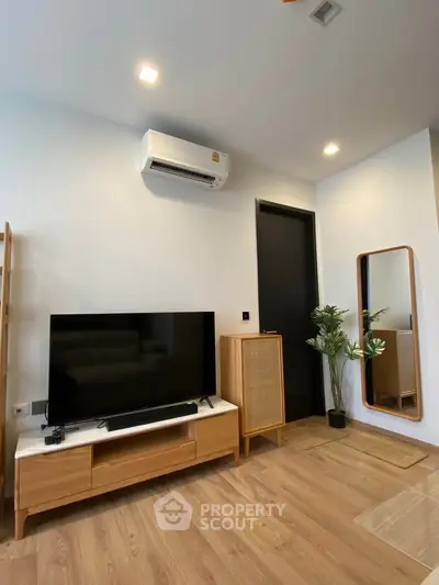 Modern living room with wooden furniture and sleek design, featuring a TV and air conditioning unit.