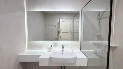 Modern bathroom with sleek design featuring a large mirror and glass shower enclosure.