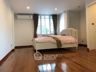 Spacious bedroom with polished wooden floors and large window for natural light.