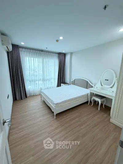 Spacious bedroom with elegant furniture and large window offering natural light
