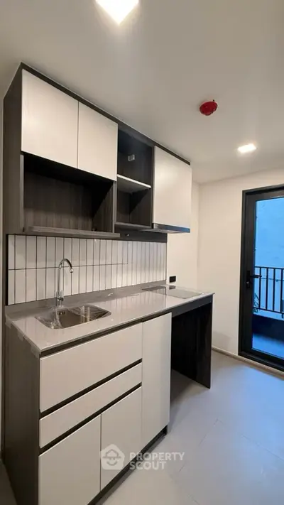 Modern kitchen with sleek cabinetry and balcony access in a contemporary apartment.