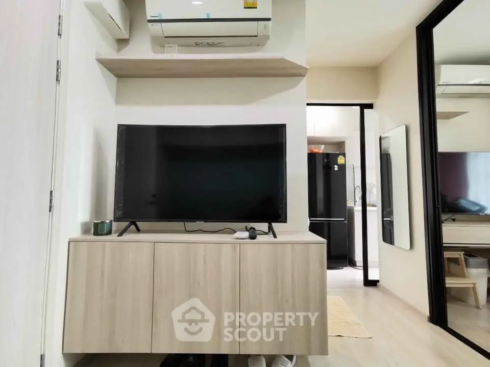 Modern living room with sleek TV setup and mirrored wardrobe in stylish apartment.