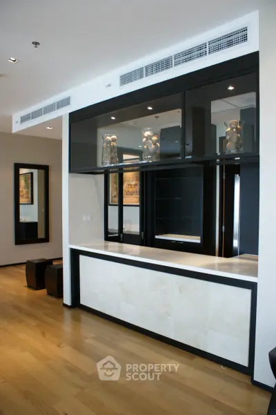 Modern interior with sleek black and white kitchen design featuring open layout and hardwood floors.