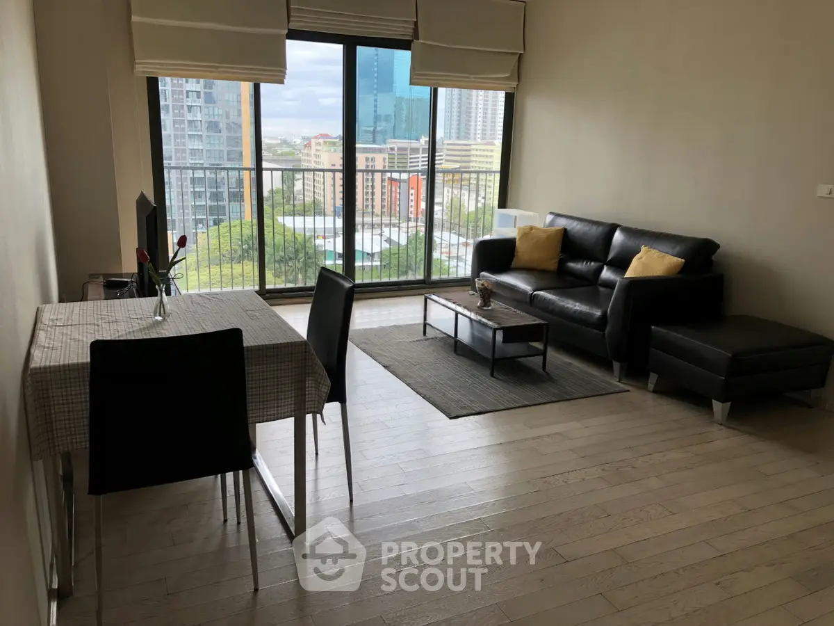 Spacious modern living room with large windows and city view, featuring sleek furniture and elegant decor.