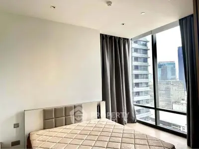 Modern bedroom with large windows offering stunning city views in a high-rise apartment.