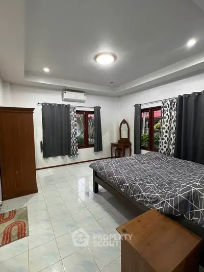 Spacious bedroom with modern decor and large windows offering natural light.
