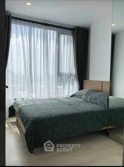 Modern bedroom with large window and stylish decor in a high-rise apartment.