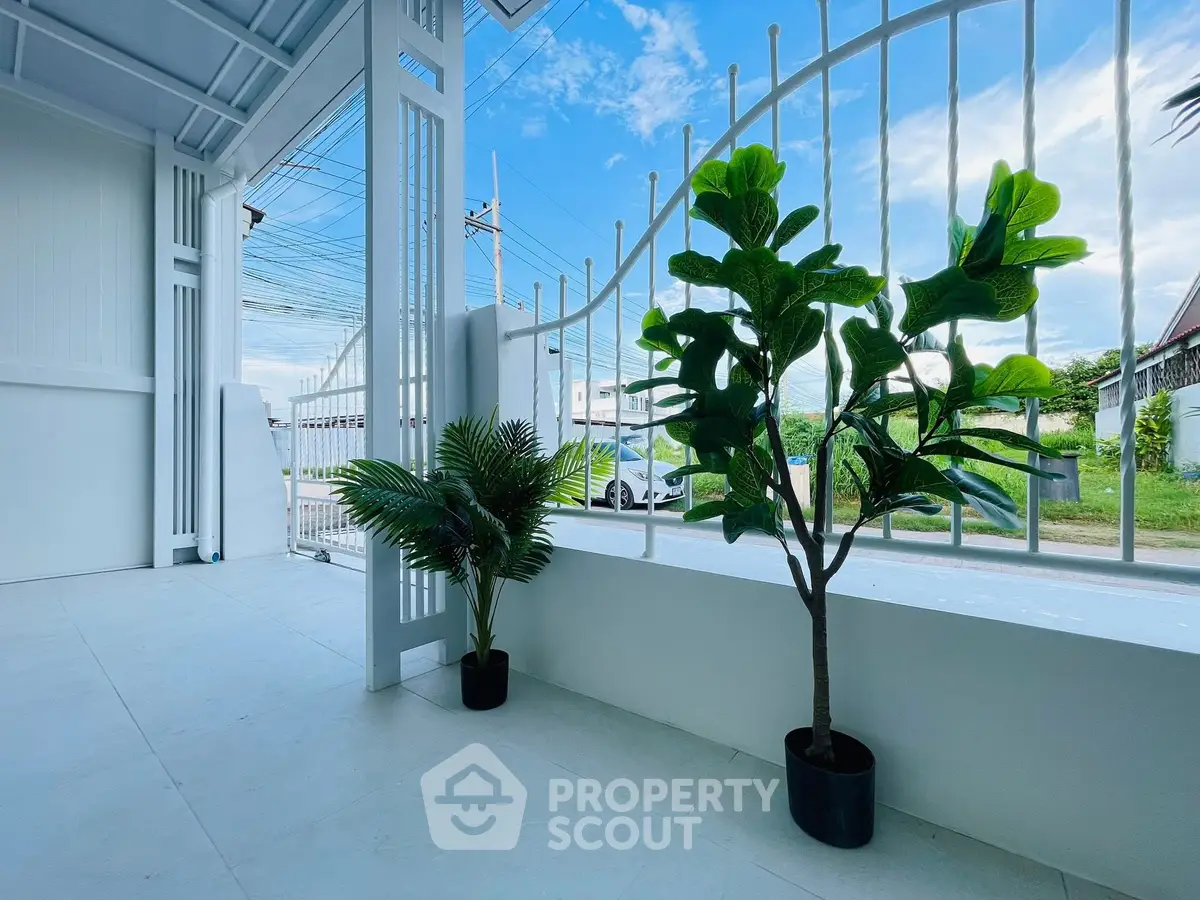 Charming garden view with potted plants and white fence in a serene residential setting.