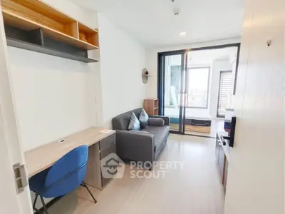 Modern apartment interior with cozy living area and study desk, featuring a sliding glass door to the bedroom.