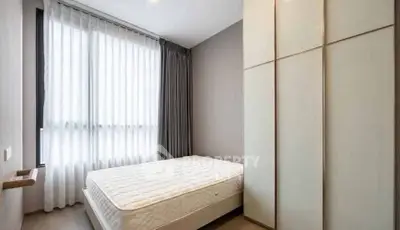 Modern minimalist bedroom with large window and ample storage space.