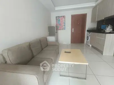 Modern living room with compact kitchen and washing machine, featuring a cozy sofa and minimalist decor.