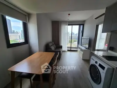 Modern living room with city view, featuring dining table, sofa, and washing machine.