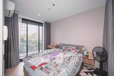 Cozy bedroom with balcony view in modern apartment, featuring stylish decor and ample natural light.
