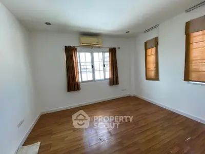 Spacious empty room with wooden flooring and large windows for natural light