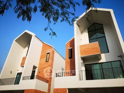 Modern architectural design of twin houses with brick and glass facade under clear blue sky.