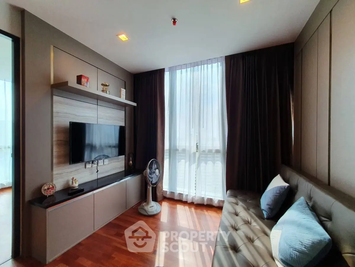 Modern living room with sleek design, featuring a wall-mounted TV, stylish sofa, and large window with natural light.