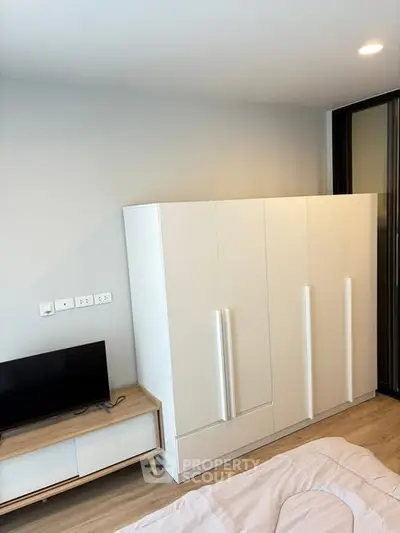 Modern bedroom with sleek white wardrobe and compact TV stand