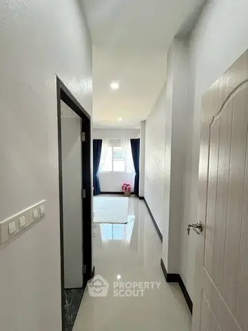 Bright hallway leading to a cozy bedroom with natural light and modern decor.