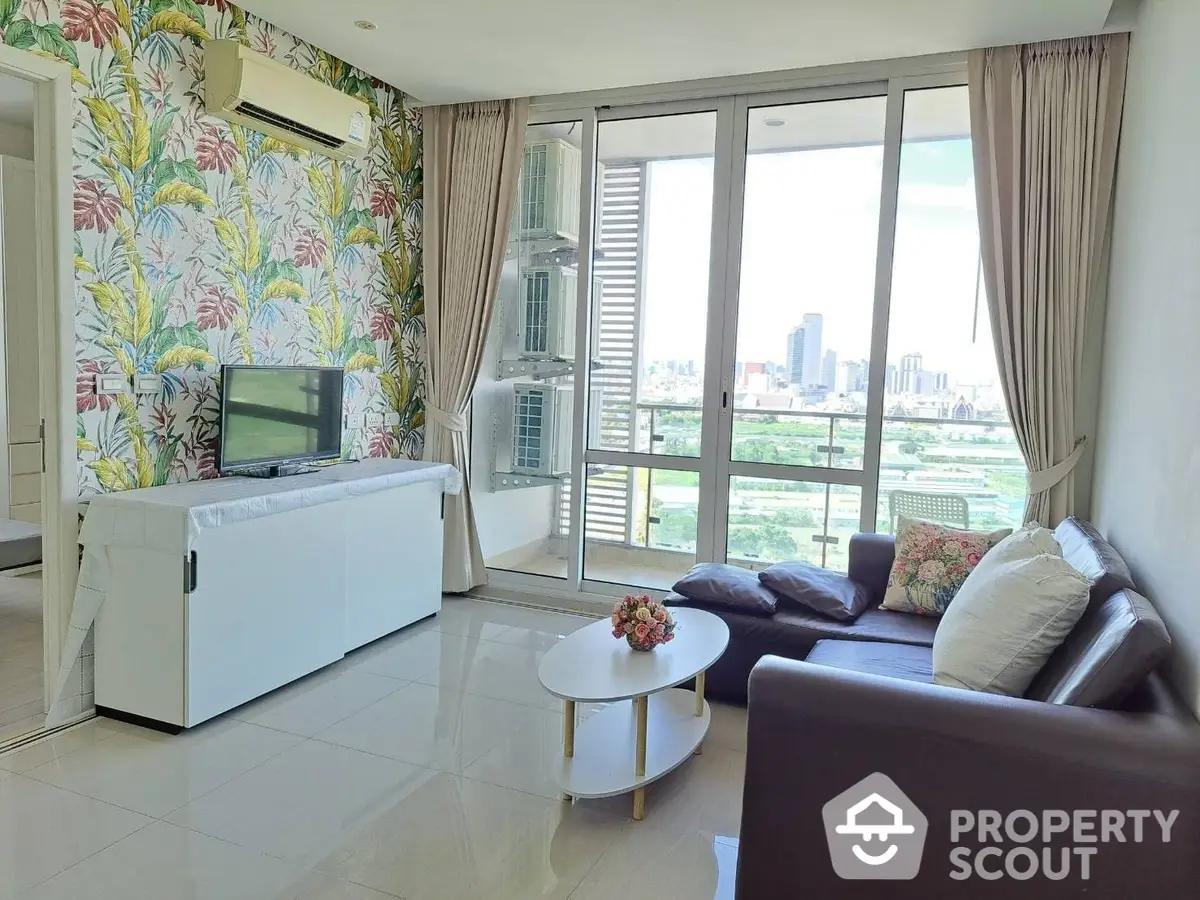 Bright and airy living room with tropical wallpaper, modern furniture, and floor-to-ceiling windows offering a city view.