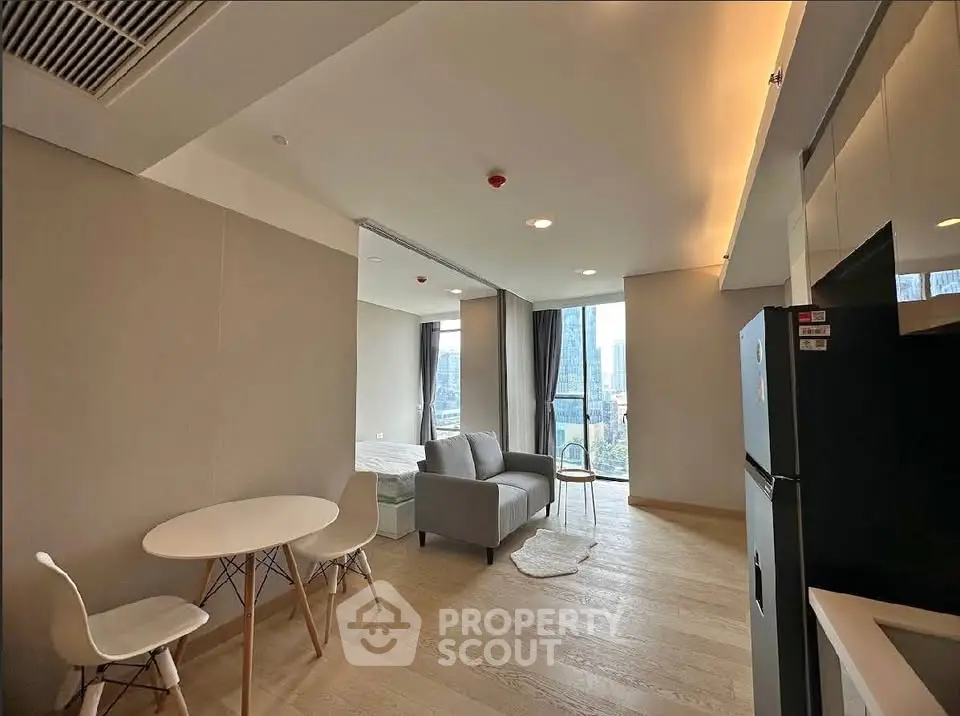 Modern open-plan living room with city view, featuring sleek furniture and natural light.