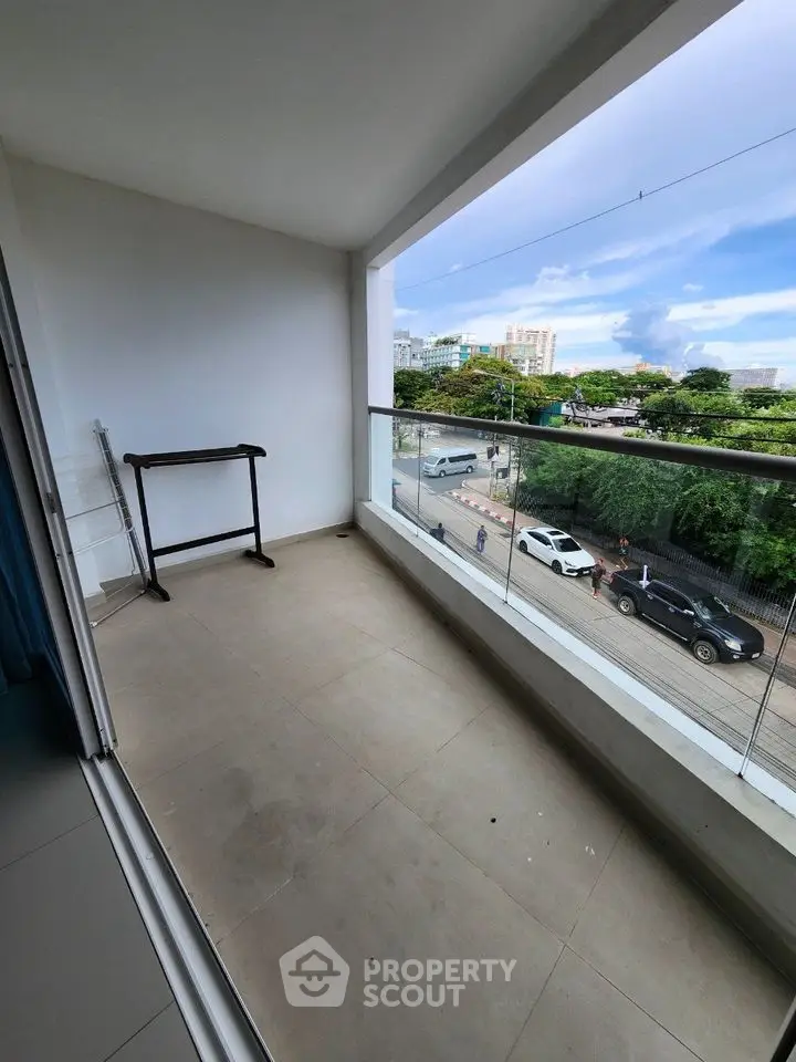 Spacious balcony with glass railing offering a scenic city view, perfect for relaxation.