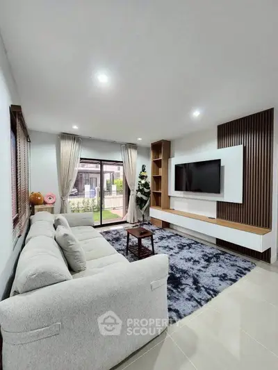 Modern living room with large sofa, wall-mounted TV, and stylish decor.